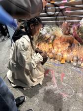 A mourner pens a farewell note to Abdul Saleh outside Sal’s Deli and Grocery.