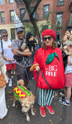 Big Apple mom and hot dog dog, Empire State Building (note the crown) behind them with a pooch dressed like King Kong, at the 2025 Halloween Dog Parade on Avenue B on Oct. 19.