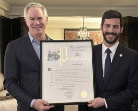 Matthew Tirschwell (left) receives a Proclamation from Assemblyman Alex Bores on April 21 for his heroic intervention this past January when he saved the life of a man who lost his leg in a subway accident.
