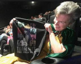 Shannon, a 54 year old psychologist, is also a die hard “Swiftie” who, before going to the sneak preview of Taylor Swift’s new record setting movie had already seen the The Eras Tour live eight times, traveling around the country with her teenage daughter Maiya. Here she shows off the tote bag she snags. Photo: Marie Pohl