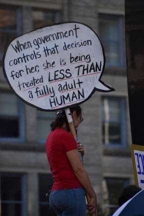 Many, like this woman, climbed up for a better view of the makeshift stage which was step up atop the steps in front of the fountain at Foley Square. Photo: Leah Foreman