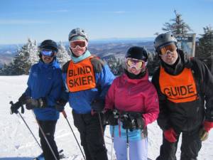 Author Ed Plumacher (second from left) at Pico Mountain in Vermont with guide Frank Kelly, who volunteers with Vermont Adaptive. The other two skiers are also volunteers, who ski in front of them and off to one side to help them avoid close contact with sighted skiers. From the annual event sponsored by United States Association of Blind Athletes.