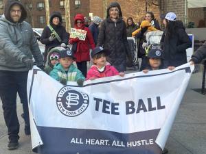 Frozen tee ballers gamely hold their division sign during the opening day parade of the Peter Stuyvesant LIttle League on March 28.