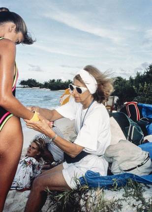 Editor Jule Campbell adjusts a bracelet on model Kathy Ireland's wrist during a <i>Sports Illustrated</i> Swimsuit Issue shoot in Saint Vincent and the Grenadines in the fall of 1989. Model Judit Masco can be seen in the background.
