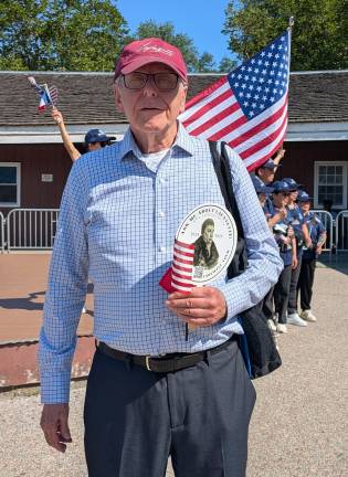 Man holding an “Ask Me About Lafayette” parade paddle.