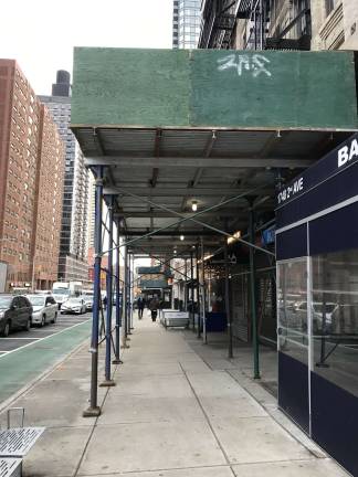A northbound view up Second Avenue from 91st Street captures an unsightly row of sidewalk sheds that has marred the vistas on Second Avenue for several years, casting shadows, scarring the streetscape and creating an unfriendly climate for pedestrians on the East Side. Photo: Douglas Feiden