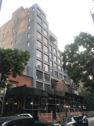 If you look closely, you can see the peaked, red brick facade of the French Evangelical Church beneath a new condo building on West 16th St. Photo: Diana DuCroz