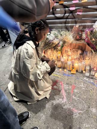 A mourner pens a farewell note to Abdul Saleh outside Sal’s Deli and Grocery.