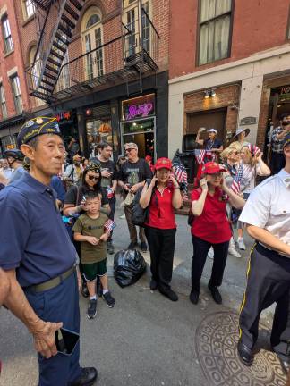 Women put fingers in their ears to lower the volume of the Factor Drum Corps on Pearl Street.