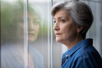 Close up thoughtful upset mature woman looking out window