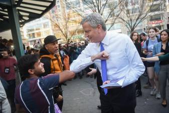 Mayor Bill de Blasio demonstrates an elbow shake and hands out fliers regarding COVID-19 preparedness in Union Square on Monday, March 9, 2020.