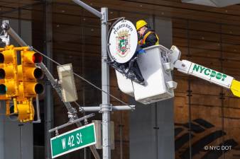 A construction worker placing the medallion on W 42nd St. one of 172 new ones along Avenue of the Americas stretching from Canal St. to 59th St. Photo: NYC DOT