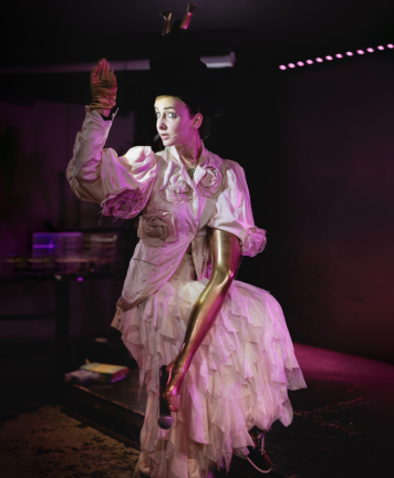 Masli on stage in costume with her golden leg-for-an-arm with mic attached.