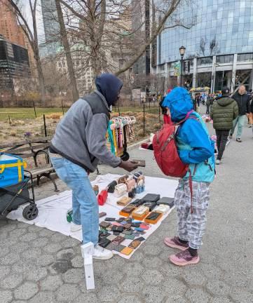 Once Upon a Time in America: Ferry ticket scams are not the only game in town. Here a vendor hawks counterfeit goods to a curious passerby. March 2025.