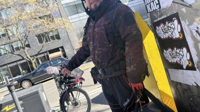 A delivery worker, who wanted to remain unnamed, trying out the charging station powered by Swiftmile on March 11 at Cooper Square in the East Village. Photo credit: Alessia Girardin.