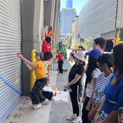 The nonprofit Publicolor is spearheading the “Fractured Spectrum” mural on Washington Street, where volunteers are transforming UPS loading gates into colorful displays.