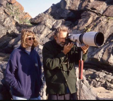 On a location, Jule Campbell during her SI career, stands next to photographer Walter Iooss as he takes the shot. Weather on the shoots was not always 85 and sunny, as the jackets attest to.