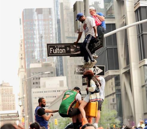 Fans climbing atop traffic signals along Fulton Street.