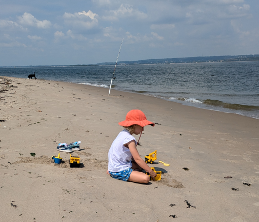A kid, a fishing pole, and a dog at Coney Island Creek Park, looking west toward Staten Island.