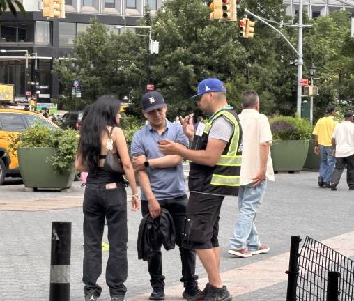 A ticket seller pitch sightseeing cruises to visitors near the South Ferry entrance to Battery Park.