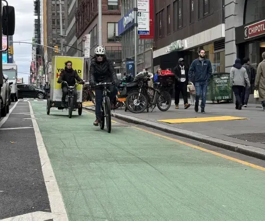 Two riders approach the intersection of Seventh Avenue and 38th Street in Midtown Manhattan.