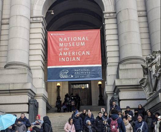 Tourists pause outside the National Museum of the American Indian while others enter.