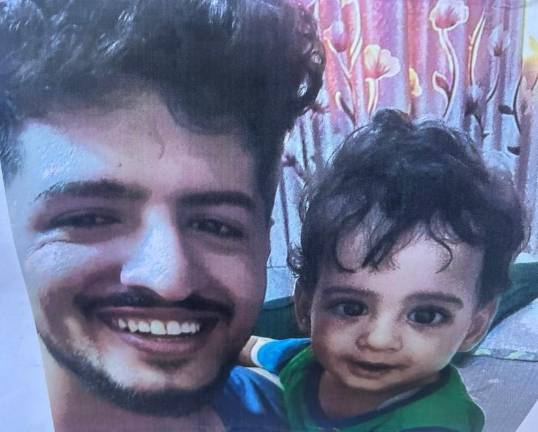 A photo of Abdul Saleh and his young son taped to a handwritten RIP sign outside Sal’s Deli.