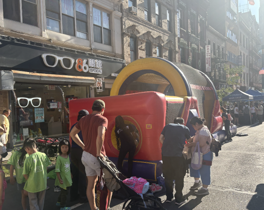 Children line up to use the other available bouncy house, closer to Bowery.