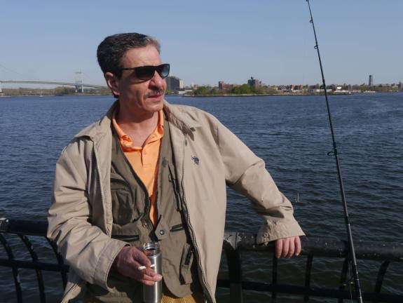 Walid Zuwaal stares down the pier at East 99th Street with his fishing line in the water. Photo: William Mathis.
