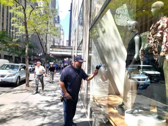 Jose Nieves cleans a retail window at Rockefeller Center. Photo: Karen Camela Watson