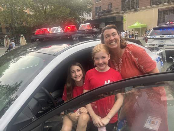 Jen Losquadro (right) brought her daughter Emma (seated in cop car) and her daughter’s friend Clara Schaffer to the 19th Precinct’s National Night Out in St. Catherine’s Park on Aug. 5.