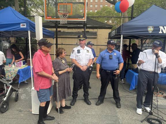 Nick Viest (far right) gets ready to present a lifetime achievement award to Barry Schneider (pink shirt) and his wife, Judy Schneider, longtime community activists and founders of the East Sixties Neighborhood Association. Inspector Neil Zuber, commander of the 19th Precinct, looks on with Police Officer Brian Larkin.
