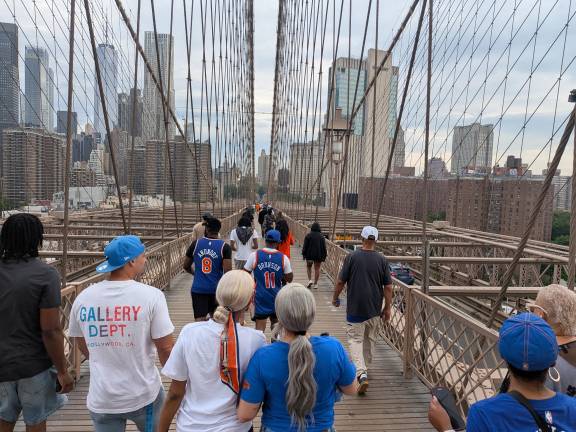 Knicks parade pilgrims walking into Manhattan over the Brooklyn Bridge.