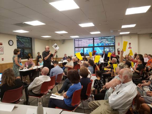 Some residents at the meeting waved yellow signs reading “Board 7 do the right thing.” Photo: Jason Cohen