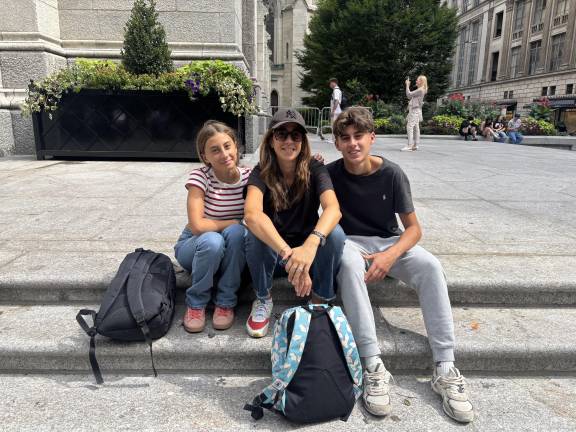 A mom, Elisa (center), visiting from Ancona, Italy, sits with her 13-year-old daughter, Ines, and 16-yearold son, Enrico on the steps of St. Patrick’s Cathedral on Aug. 29. Although several cops were standing less than 100 feet away, Elisa said she had not noticed and they were not particularly worried despite the Minneapolis church shooting.