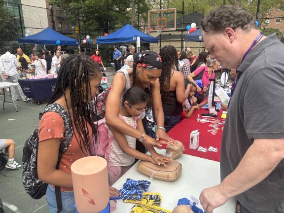 A mom assists a youngster in the proper way for a kid to administer CPR while Robert Curran of the injury prevention trauma center at NewYork-Presbyterian ambulatory service looks on.