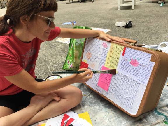 Sara Gozalo, supervising co-coordinator for the city-based New Sanctuary Coalition, decorating the suitcase that she is going to carry to a July 26 march in support of immigrants and would-be deportees. "We have friends who have told us, 'when you are in detention and you get a letter, that's like a treasure,'" she said. Photo courtesy of Sara Gozalo