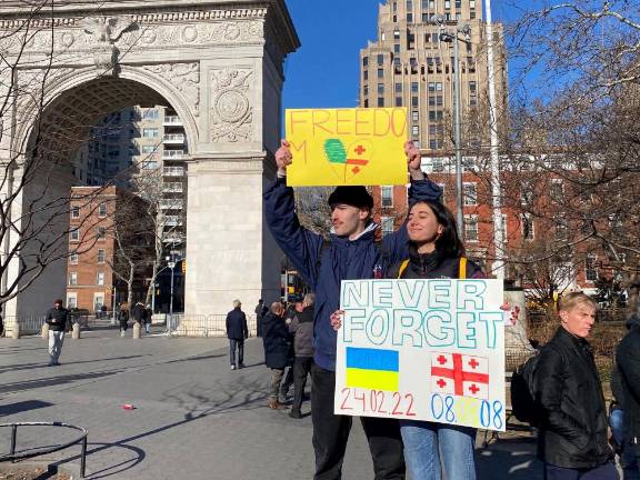 Students hold signs reading “Freedom” and “Never Forget: 24/02/22.”