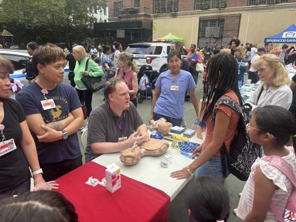 Robert Curran from the injury prevention trauma center at NewYork-Presbyterian gives a young girl named Mikela instructions on CPR during the 19th Precinct’s National Night Out.