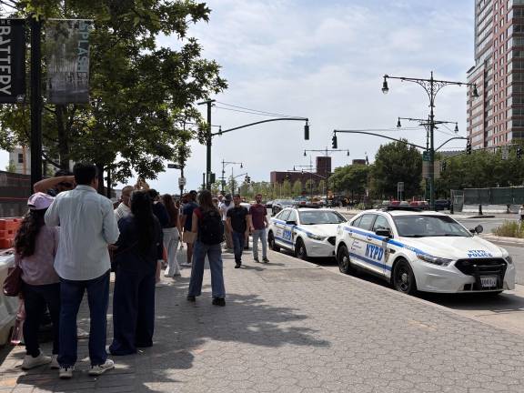 Visitors wait in the heat outside Battery Park before boarding sightseeing cruises.