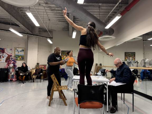 Cast of <i>Domino Effect </i>rehearses a scene at central table.