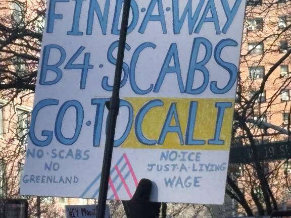 As the strike by nurses drags on, other political issues are percolating on the picket line. One picket line worker added to her sign: “No ICE, Just a Living Wage” and “No Scabs. No Greenland.”