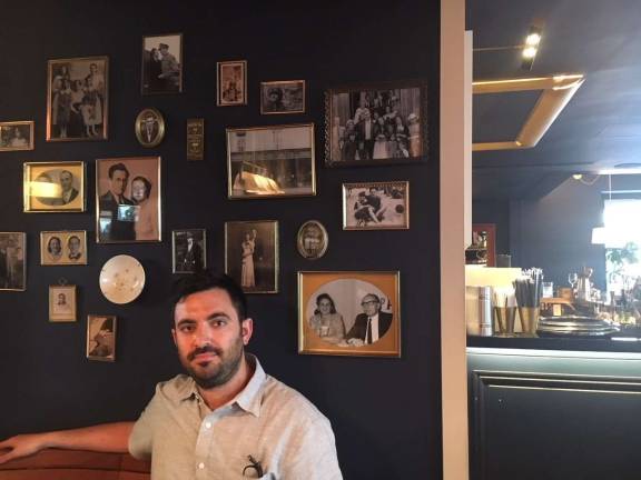 Sam Nidel, co-owner of Motel Morris and The Commons, sits by a wall of family photos inside Motel Morris.&#xa0;Photo: Michael DeSantis