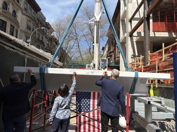 Members of the project team sign the last steel beam before it is installed atop the new four story wing of the society at 170 Central Park West.
