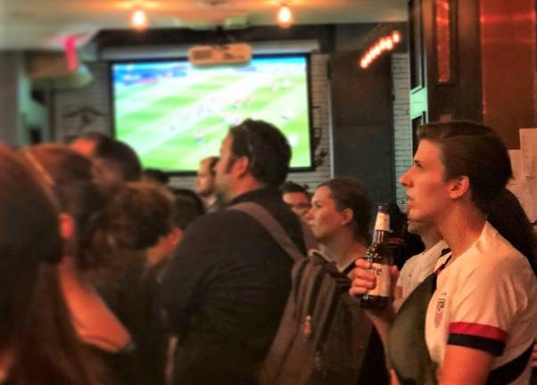 In the crowded Smithfield Hall in Chelsea, Katie Mathews, right, watches the U.S. Women’s National Team in their 3-0 victory over Chile. Photo: Emily Higginbotham
