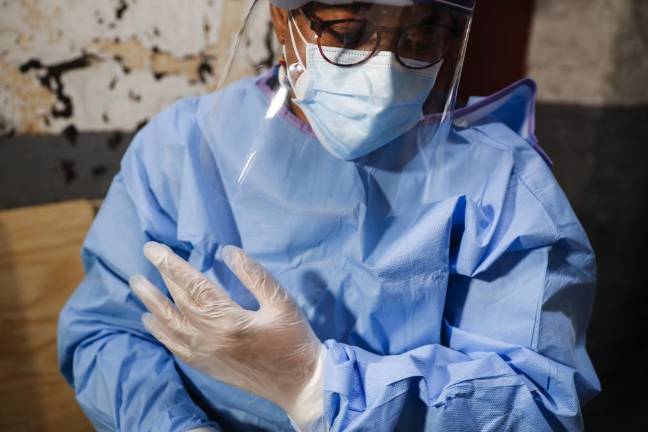 Ruth Caballero, a nurse with The Visiting Nurse Service of New York, suits up in protective equipment before treating a COVID-19 patient on her rounds in upper Manhattan in New York. Home care nurses, aides and attendants are now taking on the difficult and potentially dangerous task of caring for coronavirus patients.