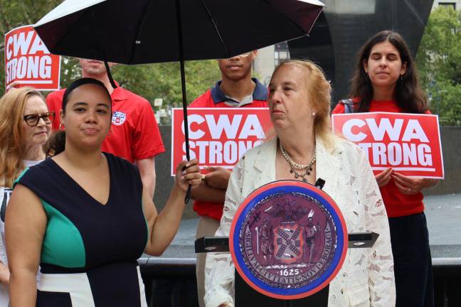 City Council Member Gale Brewer at the podium. Council Member Carmen De La Rosa holds the umbrella.