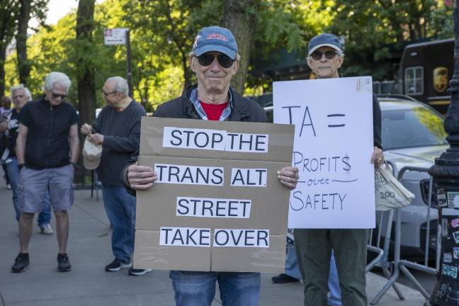 Demonstrators hold signs outside the New-York Historical Society during a protest over e-bike safety and bike lane policies.