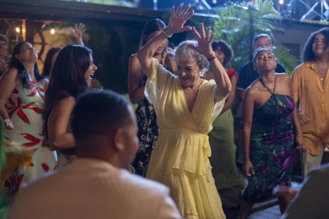 A scene from “Hurricane Seasons,” directed by Nicole Gomez-Fisher and written by Javier Ortiz. Angela Camacho (Priscilla Lopez) in yellow celebrates with her granddaughter Issa (Jearnest Corchado) and others in Puerto Rico.