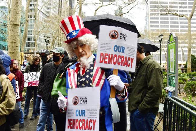 Mark Mindek came dressed as Uncle Sam with a sign saying “Hands Off Our Democracy.”